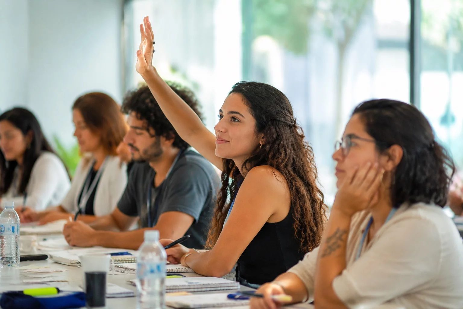 Estudante levantando a mão em uma mesa de seminário coberta de anotações